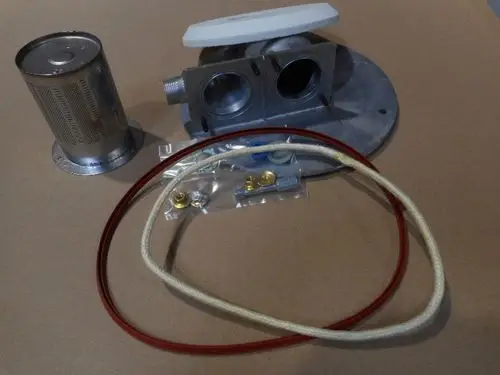 Remeha-Brennerbestandteile bestehend aus einem Filter, einer Montageplatte, zwei Anschlüssen, Dichtungen und Schläuchen, angeordnet auf einer neutralen Unterlage.